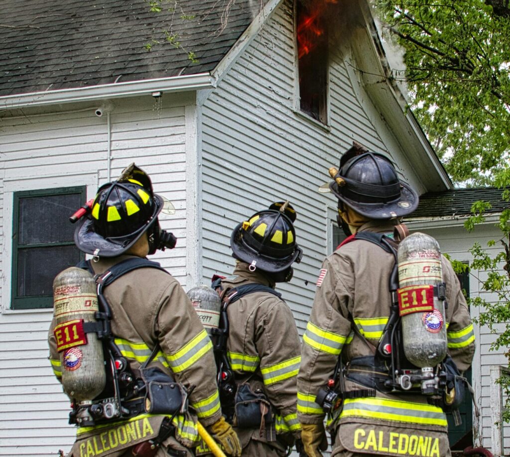 Firefighters put out a house fire. The homeowners should ask their insurance about temporary housing in an RV.